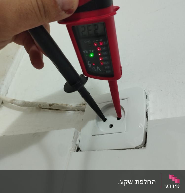 מד מתח מחובר לשקע חשמלי בקיר